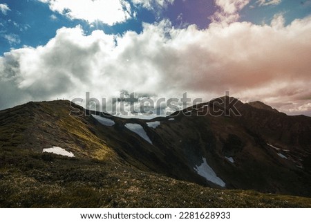 Ridge with remaining glaciers landscape photo. Beautiful nature scenery photography with clouds on background. Ambient light. High quality picture for wallpaper, travel blog, magazine, article