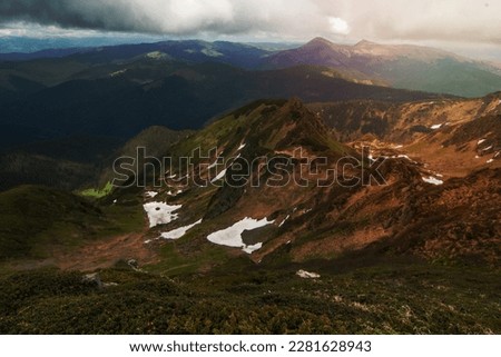 Remaining snow beside mountain ridges landscape photo. Beautiful nature scenery photography with blurred background. Ambient light. High quality picture for wallpaper, travel blog, magazine, article