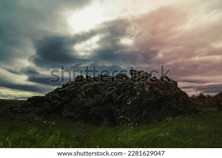 Old rock in green field landscape photo. Beautiful nature scenery photography with overcast sky on background. Idyllic scene. High quality picture for wallpaper, travel blog, magazine, article