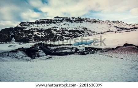 Glacier in rock mountain bottom landscape photo. Beautiful nature scenery photography with cloudy sky on background. Idyllic scene. High quality picture for wallpaper, travel blog, magazine, article