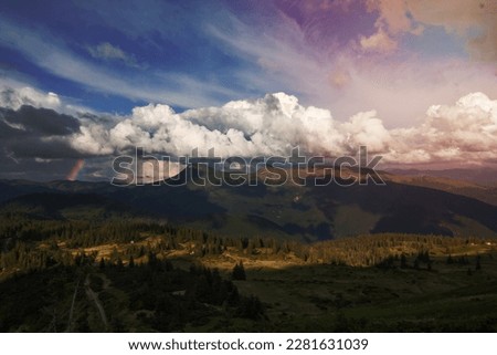 Fluffy clouds above valley landscape photo. Beautiful nature scenery photography with rainbow on background. Ambient light. High quality picture for wallpaper, travel blog, magazine, article