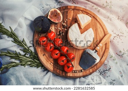 Close up round picnic cheese platter with tomatoes and figs concept photo. Top view photography with blurred background. High quality picture for wallpaper, travel blog, magazine, article