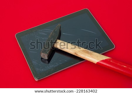 Hammer on a broken touch screen tablet on a red alerted important dangerous serious background suggesting not an accident and glass replace