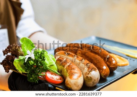 Spicy homemade Baked sausages with baked vegetables and spices on a brown wooden background. 