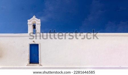 Cyclades, Greece. Small white church wall and belfry against blue sky, sunny day. Copy space