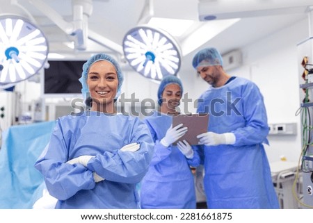 Portrait of female woman nurse surgeon OR staff member dressed in surgical scrubs gown mask and hair net in hospital operating room theater making eye contact smiling pleased happy looking at camera Royalty-Free Stock Photo #2281661875