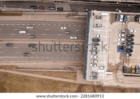 Drone photography of highway going in a tunnel under office space and parking place on a roof. Directly above