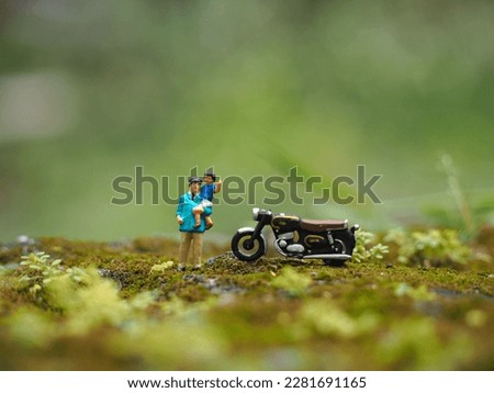 Toy photography concept. Unfocus green grass and mini toy. Background is blurred.