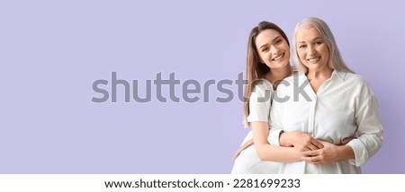 Portrait of young woman and her mother on lilac background with space for text