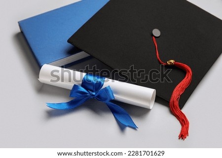 Diploma with blue ribbon, graduation hat and book on white background Royalty-Free Stock Photo #2281701629