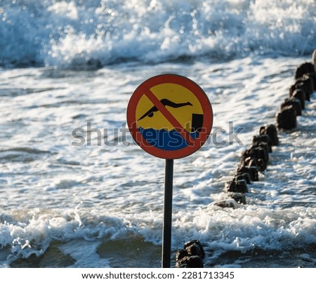 Wooden breakwaters. Sign forbidding jumping from breakwaters into the sea. Beach hazard warning sign.