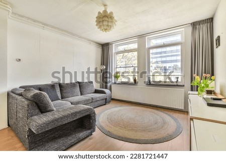 a living room with a couch and rug on the floor in front of a large window looking out onto the street