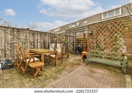a backyard area with a table, chairs and bench in the middle part of the yard that is fenced off