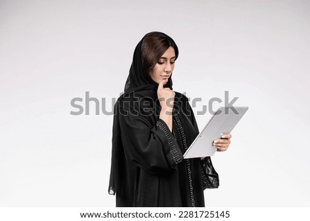 Arab woman using tablet or laptop wearing Abaya.