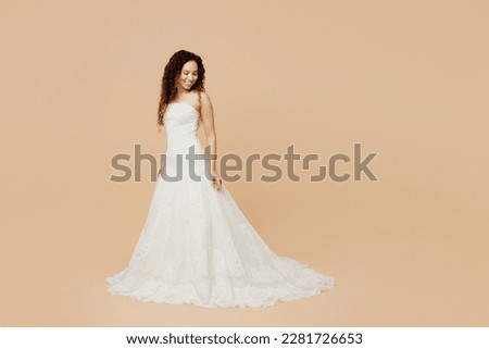 Full body sde view elegant beautiful happy young woman bride wear wedding dress posing look camera isolated on plain pastel light beige background studio portrait. Ceremony celebration party concept