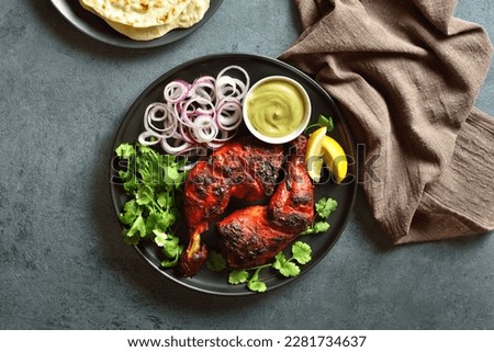 Tandoori chicken served with cilantro and onion on plate over dark stone background. South asian dish of marinated chicken meat. Top view, flat lay
 Royalty-Free Stock Photo #2281734637