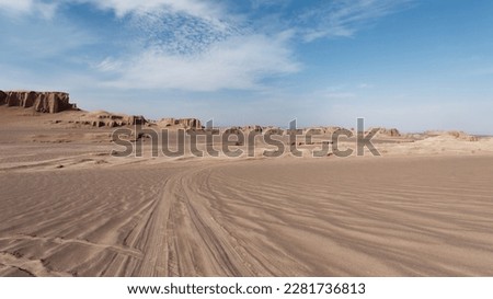  Low-angle view of the car trails in the sand and formations known as Kaluts in the background, Dasht-e Lut Desert, Iran Royalty-Free Stock Photo #2281736813