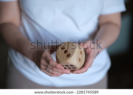 An enigmatic woman gripping a massive die, illustrating the unforeseen nature of life. Embracing the unknown: Techniques for thriving in a world of uncertainty Royalty-Free Stock Photo #2281745589