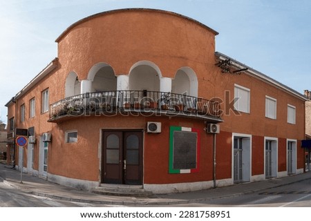Trebinje old round corner house with arch balcony painted with rough red plaster facade view