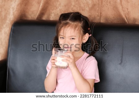 A girl is raising a glass of milk.
: picture in Thailand