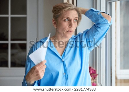 Menopausal Mature Woman Having Hot Flush At Home Cooling Herself With Letters Or Documents Royalty-Free Stock Photo #2281774383