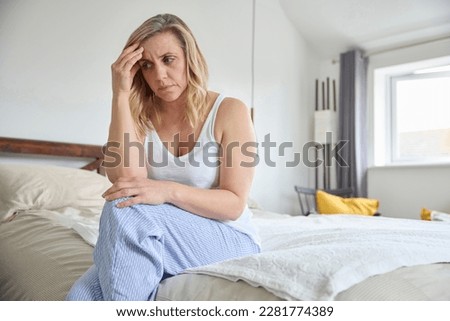 Menopausal Mature Woman Suffering With Low Mood And Anxiety Sitting On Bed At Home  Royalty-Free Stock Photo #2281774389