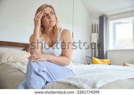 Menopausal Mature Woman Suffering With Low Mood And Anxiety Sitting On Bed At Home  Royalty-Free Stock Photo #2281774399