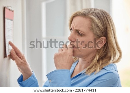 Forgetful Menopausal Mature Woman With Poor Memory Looking At Calendar At Home Royalty-Free Stock Photo #2281774411