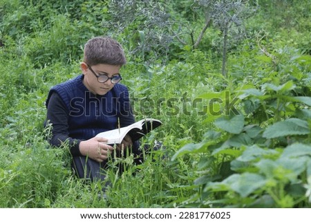 A boy is reading a book in nature. Relaxing on the grass in the garden. Selective focus. 