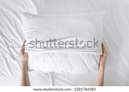 cropped shot of female hands putting fresh pillowcase on soft cushion on bed sheet background at home, make bed concept, housekeeping, top view Royalty-Free Stock Photo #2281784383