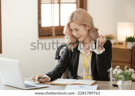 Close up on laptop in office, Asian happy beautiful businesswoman in formal suit work in workplace. Attractive female employee office worker smile.