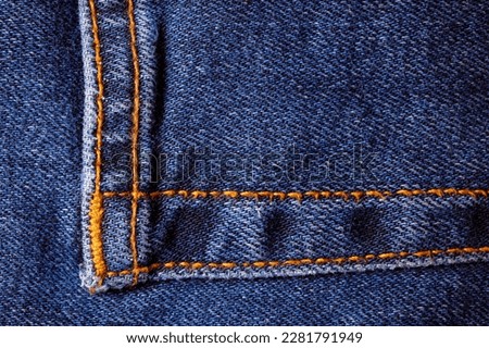 Worn denim trousers. Machine stitch close up. Denim texture in blue. The concept of repairing old clothes. Sewing factory. Fashionable aging clothes.