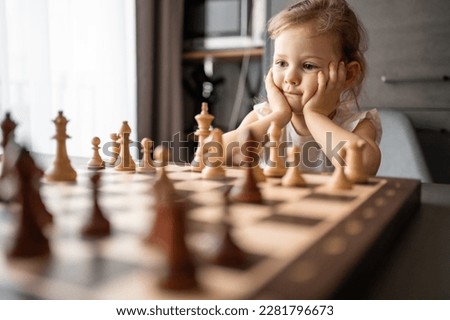 Little girl playing chess at the table in home kitchen. The concept early childhood development and education. Family leisure, communication and recreation. High quality photo