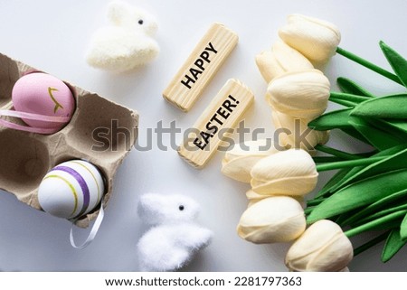 Colorful decorative eggs and HAPPY EASTER text close-up, against the background of a white rabbit. High quality photo