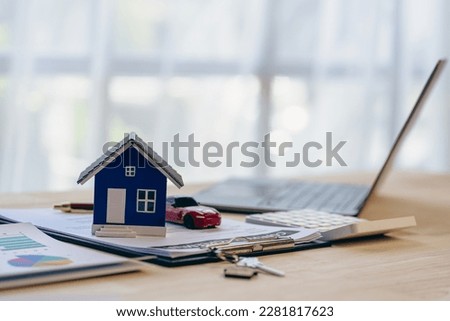 House model and car, laptop contract document on table, real estate business concept