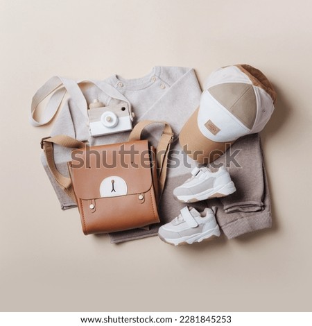 Fashion children's clothing, shoes. Set of knitted baby clothes. Newborn brown jumper, pants, kid bag on beige background. Top view, flat lay. Fashion kids outfit and accessories. Royalty-Free Stock Photo #2281845253
