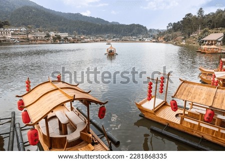 Ban Rak Thai, a beautiful village within Mae Hong Son province, Thailand, with scenic lake. Traditional boats are available for hire. Chinese words translated as Guest in English language. Royalty-Free Stock Photo #2281868335