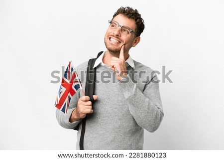 Brazilian man holding an United Kingdom flag over isolated white background thinking an idea while looking up Royalty-Free Stock Photo #2281880123
