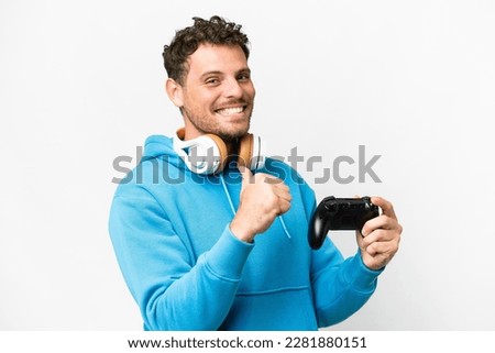 Brazilian man playing with a video game controller over isolated white background proud and self-satisfied
