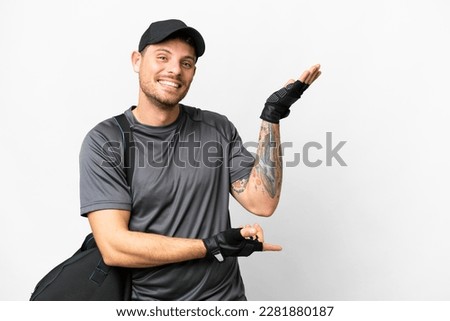 Young sport man with sport bag over isolated white background extending hands to the side for inviting to come