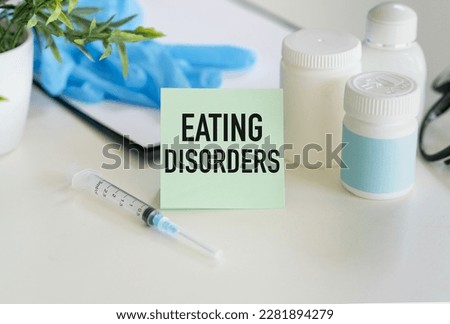 Eating Disorders text on a card on the table next to a jar of medicine and scattered pills