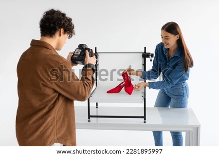 Professional male photographer and his female assistant doing content photoshoot for shoes, woman styling and helping while working in team in photostudio Royalty-Free Stock Photo #2281895997