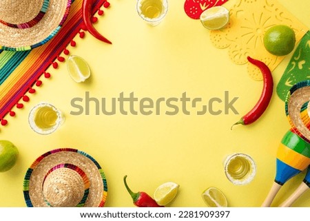 Spice up your celebration with colorful Cinco de Mayo-themed flat lay! Featuring a sombrero, poncho, maracas, tequila shots, lime, chili peppers on a yellow background space for text Royalty-Free Stock Photo #2281909397