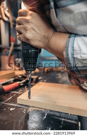 Woman drilling a hole in the wood with a drill