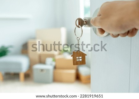 Moving house, relocation. The key was inserted into the door of the new house, inside the room was a cardboard box containing personal belongings and furniture. move in the apartment or condominium Royalty-Free Stock Photo #2281919651