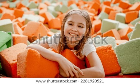 Pretty child girl in trampoline park having fun in colorful soft cubes and smiling. Cute preteen kid enjoying amusement activities Royalty-Free Stock Photo #2281920521