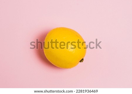 Juicy lemon on pink paper background with copy space.