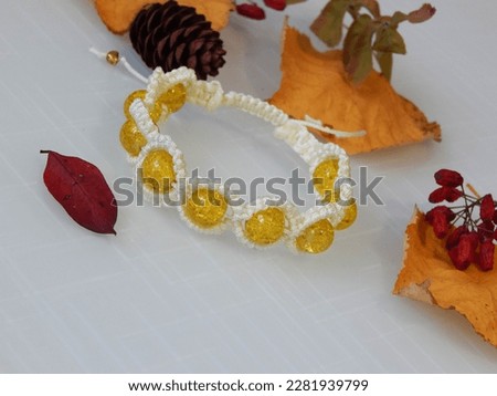 Beautiful yellow bracelet on a white. Sunny bracelet and leafs
