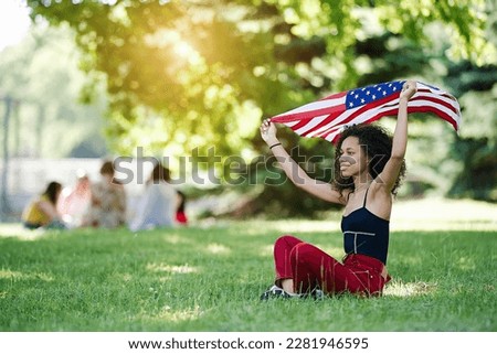 Young African american woman is waving American flag on top of at nature background. USA resident, US citizen. Immigration concept	                              