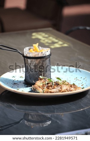 A delicious dish with a beautiful minimalism-style serving with potato dishes in a vase and a meat steak made of marble beef